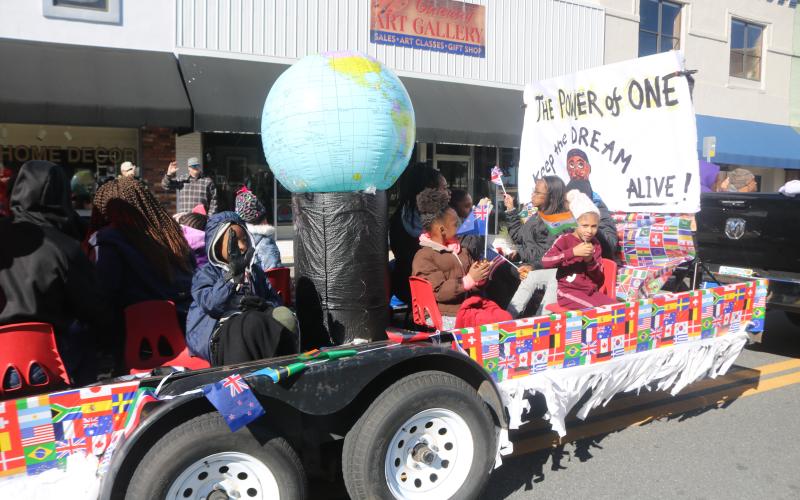 Youngsters on the New Dayspring Missionary Baptist Church float hold flags representing various nations during Monday’s parade, the theme of which was: “The Power of One.” (TONY BRITT/Lake City Reporter)