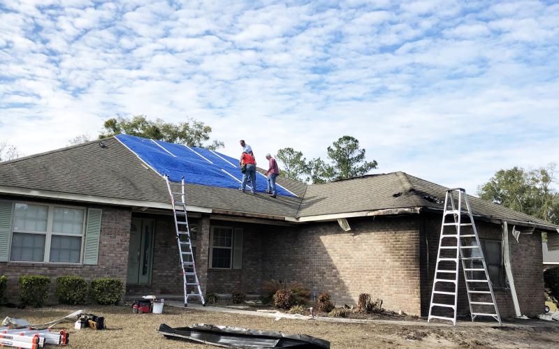 Among those volunteering to patch the roof of a home hit by a plane Saturday were Bill Brinkley (from left), Alvin Hitson and Mark Nodes. Photo by Robert Bridges/Lake City Reporter