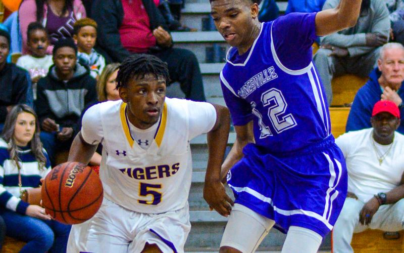 Columbia guard Darrien Jones drives by Gainesville’s Alex McCray on Tuesday night. (THOMAS RICKS/Special to the Reporter)