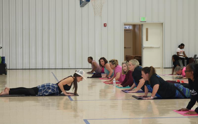 Yoga instructor Lisa Lizotte leads school district employees through stretches Tuesday afternoon in the Parkview Baptist Church gymnasium. Twenty-five people attended the first yoga class, offered as part of a school district wellness initiative. (TONY BRITT/Lake City Reporter)