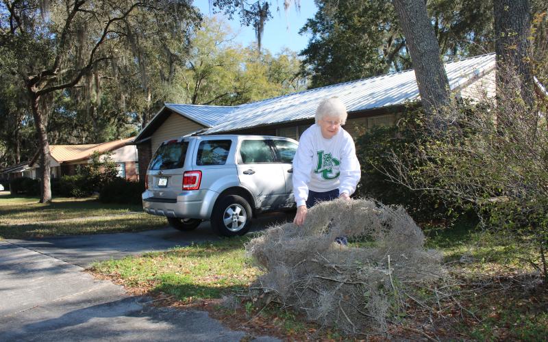 Joyce Baskette adds more debris to a pile of limbs, branches and clumps of moss that she created while picking up debris that fell in her Lake City yard Thursday when high winds hit the area. (TONY BRITT/Lake City Reporter)