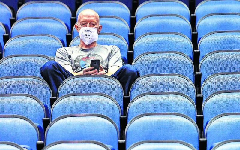 Mike Lemcke, from Richmond, Va., sits in an empty Greensboro Coliseum after the games were canceled at the Atlantic Coast Conference basketball tournament in Greensboro, N.C. (BEN McKEOWN/Associated Press)