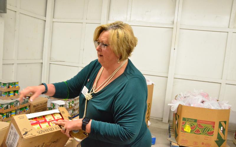 Catholic Charities Regional Director Suzanne Edwards inspects a carton of raisins delivered to the organization’s Florida Gateway Food Bank. Demand for food assistance is surging while the economy is in a holding pattern. (CARL MCKINNEY/Lake City Reporter)