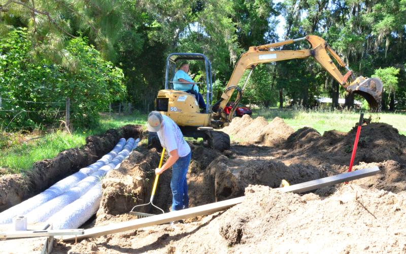 Charles Peloni, owner of Peloni’s Pumping and Portable Toilets, pictured on the right operating heavy machinery, installs a new septic tank with his employee and stepson, Joseph Creeley, pictured on the left. Peloni says business has slowed down in some aspects but picked up in others during the pandemic, resulting in revenue staying steady. (CARL MCKINNEY/Lake City Reporter)