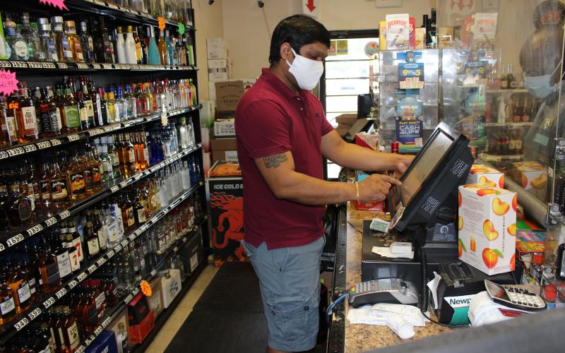 Wearing a protective mask when facing customers has become a daily part of business for Dharmendra Thakor, manager of A&amp;D Discount Liquor in downtown Lake City. Thakor also installed a plexiglass shield at his customer service area to help protect him and his customers during the covid-19 pandemic. (TODD WILSON/Lake City Reporter)