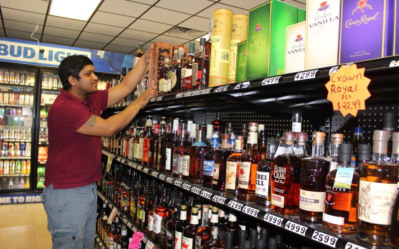 Dharmendra Thakor, manager of A&amp;D Discount Liquor, at the corner of Main Street and U.S. 90, straightens a top-shelf bottle of Booker’s bourbon at his store in downtown Lake City Friday afternoon. Thakor said since the coronavirus pandemic hit his business has been good, as people have increased spending on liquor and beer, buying larger quantities and more frequently. (TODD WILSON/Lake City Reporter)