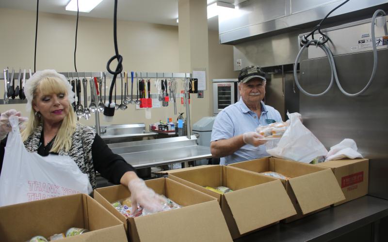 Rose Taylor and Michael Rogers, Columbia County Senior Services drivers, bag frozen meals and other staples for clients of the agency’s Meals on Wheels home-delivery program. The agency has seen a 25% increase in the number of meals it delivers in recent weeks. (TONY BRITT/Lake City Reporter)