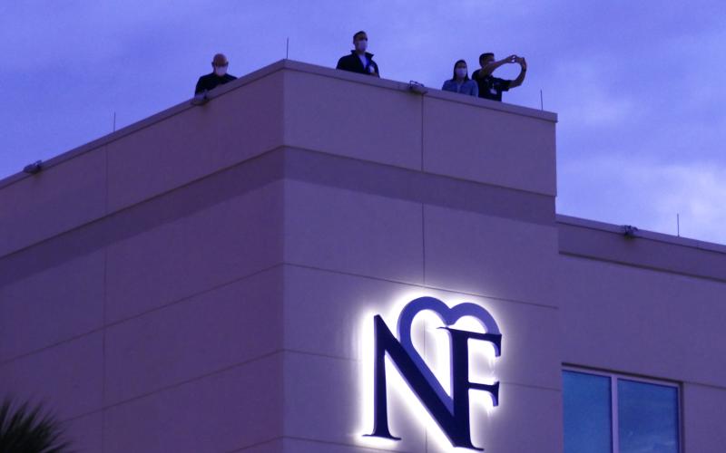 LCMC officials watch the event unfold from the hospital’s roof Sunday night. The Orchard Community Church, which organized the event, estimated that a couple hundred automobiles participated. (TRAVIS LEE/Special to the Reporter)