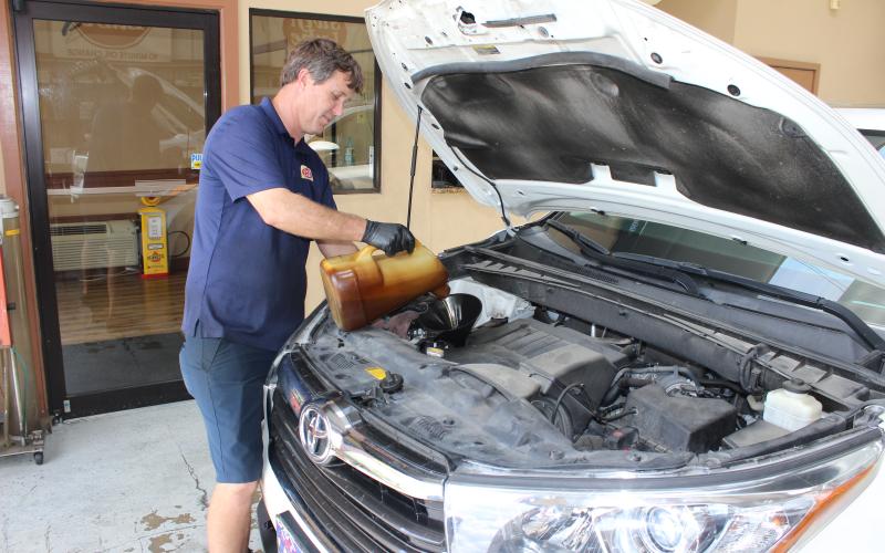 Swift Lube 10-Minute Oil Change co-owner Kevin Swisher pours fresh oil into an SUV at the company’s business location on Knox Street in Lake City Thursday.          morning. Swisher, who owns the business with his brother, Benji, said the volume of their business has declined sharply this month from the “safer at home” order in place statewide. (TODD WILSON/Lake City Reporter)
