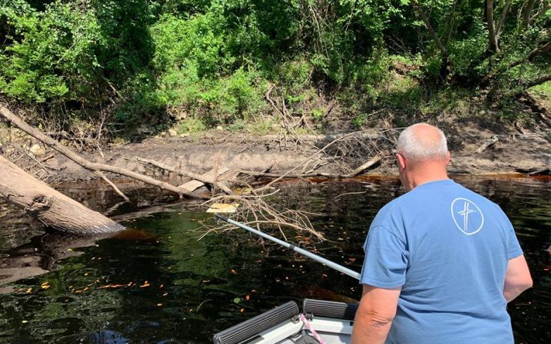 Cpl. Chuck Tompkins of the Suwannee County Sheriff’s Office snags another sign from the Suwannee. (COURTESY SCSO)