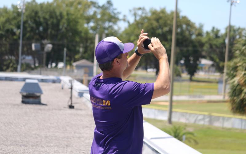 CHS Principal Trey Hosford, on the roof of the school, captures a photo of a banner carried by a plane he hired in recognition of the Class of 2020. (CARL MCKINNEY/Lake City Reporter)