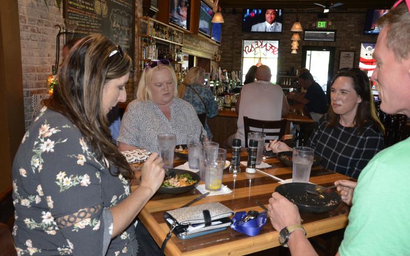 Local tourism officials finish off their salmon bowls at Marion Street Bistro on Monday. The man facing away from the camera is the county’s sports marketing director, Alden Rosner. On the back right is Paula Vann, executive director of the county’s Tourist Development Council. They were joined by Michelle Moore, front left, and Kim Goldsmith, back left. (CARL MCKINNEY/Lake City Reporter)