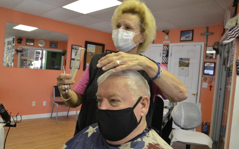 Mizz Wezzie cuts the hair of a customer, Jim Martin, who has been going to her salon for years. Miss Wezzie bought a $300 set of new blades in anticipation. (CARL MCKINNEY/Lake City Reporter)