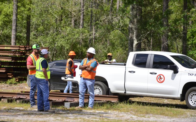 A construction crew gathers Thursday on the north side of U.S. Highway 90, where work is underway to construct a rail spur connecting the North Florida Mega Industrial Park to cities throughout the region. A stack of railing is visible in the back left. The project has been years in the making, with county officials frequently vowing it will pave the way for major economic growth in the community. (CARL MCKINNEY/Lake City Reporter)
