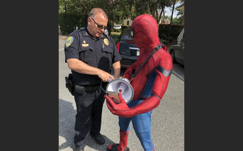 LCPD Assistant Chief Gerald Butler shows Spiderman, aka Todd Franklin, how to work the bullhorn the department lent him for a protest. (ROBERT BRIDGES/Lake City Reporter)