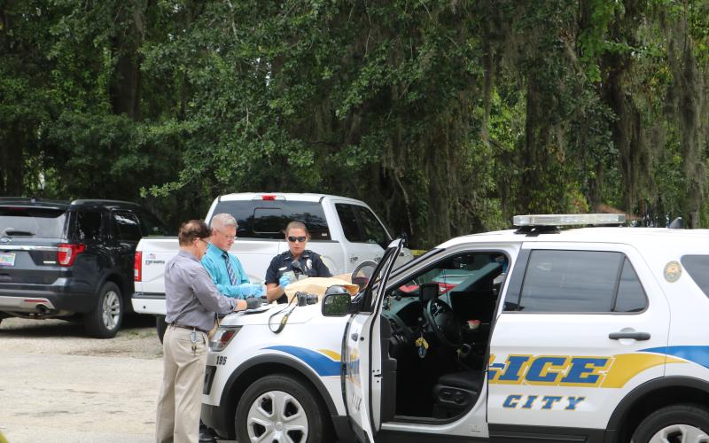 Phil Dorris, LCPD evidence technician (from left), Lt. Andy Miles and Officer Erica Bass count stolen money from the Ameris Bank robbery Wednesday morning. The loot was recovered after a suspect was apprehended about a block south of the bank. (TONY BRITT/Lake City Reporter)