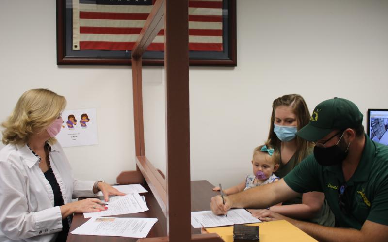 Lori Koon (clockwise from left), deputy clerk, helps Anna Marlowe, Vera Platt and Donald Platt as they complete an application for a marriage license while at the Columbia County Clerk of Courts Record Division Office on Wednesday. Due to budget cuts, the clerks office is now closed on Fridays. (TONY BRITT/Lake City Reporter)