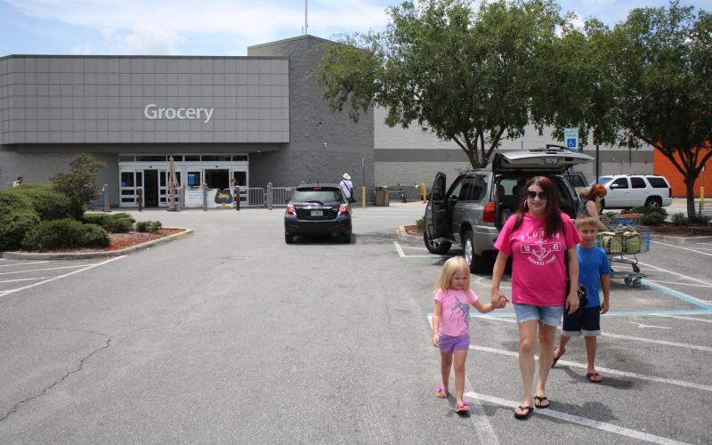 Jordyn Fletcher, 4, walks in the Lake City Walmart Super Center parking lot with Rebecca Fletcher and Jayden Fletcher, 9, Wednesday afternoon while the family was shopping at Walmart without masks. On Wednesday Walmart and Sam’s Club announced that effective July 20, customers will be required to wear face coverings when shopping at its stores. (TONY BRITT/Lake City Reporter)