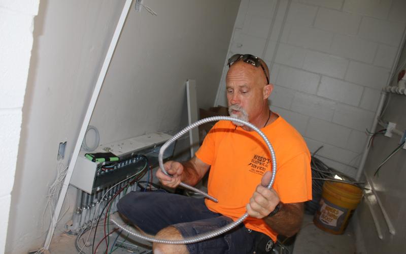 David Warren, a Wood’s Electrical Services employee, installs electrical wires in the Summers Elementary School kitchen Wednesday afternoon. The kitchen was recently gutted and will be updated for when students return to school. It’s the first major renovation project on the school’s kitchen in the past 25 years. (TONY BRITT/Lake City Reporter)