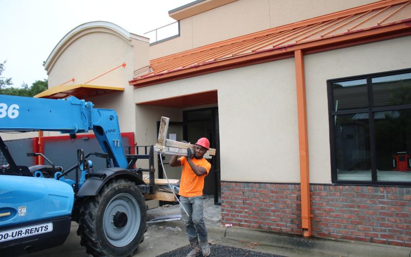 Taylor Andrews, a Great Southern Demolition employee, carries debris to a dumpster Wednesday afternoon while completing demolition work on the building that will become the Chipotle Mexican Grill. (TONY BRITT/Lake City Reporter)