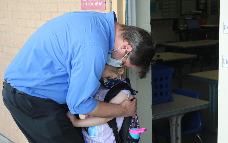 Michael Brock hugs his daughter Artie Brock as he drops her off at a Summers Elementary School kindergarten classroom Monday morning. The Columbia School District started the 2020-21 school year Monday. (TONY BRITT/Lake City Reporter)