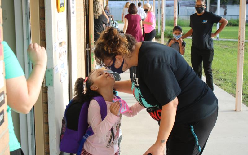 Deziraye Bristol (left) gets a kiss from her mother April Arce before she goes into her Summers Elementary School kindergarten classroom on Monday morning. Due to safety protocols implemented by the school district, parents were only allowed to walk pre-kindergartners and kindergartners to class for the first day of school. (TONY BRITT/Lake City Reporter)