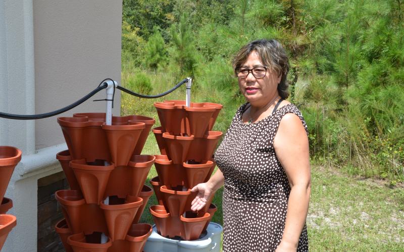 Yaping Morgan shows off the Smart Farm system, which includes ‘Mr. Stacky’ planters that can be stacked on top of each other, allowing water to flow easily from one to another. (CARL MCKINNEY/Lake City Reporter)