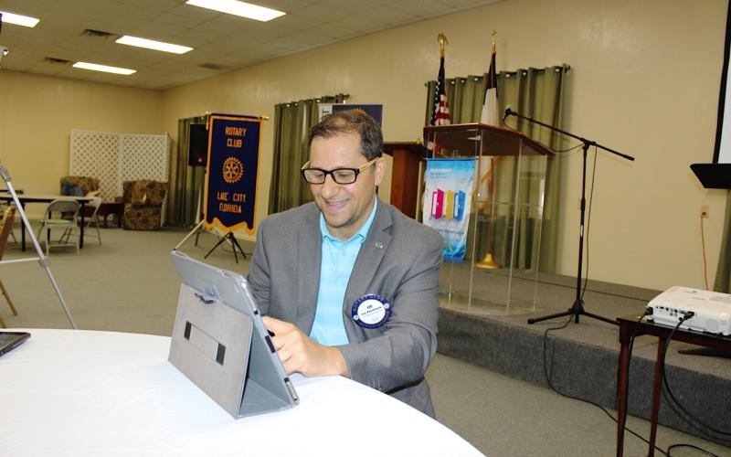 Rotary Club of Lake City President Lee Pinchouck talks to members connecting to a club meeting via Zoom technology as he positions an iPad to video broadcast club activities from the podium behind him prior to the start of Thursday’s meeting. The Rotary Club of Lake City is offering its members hybrid meetings each week either in person or virtually via Zoom. (TODD WILSON/Lake City Reporter)