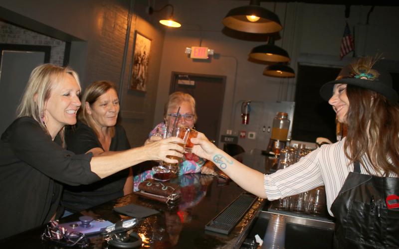 Sonja Mattingley (clockwise from left), Karen Raulerson, and Kathy Kaz, patrons at Prohibition, share a toast with Brooke Stalnaker, the establishment’s bar manager, Tuesday night. The bar opened Monday in the Blanche Hotel building downtown. (TONY BRITT/Lake City Reporter)