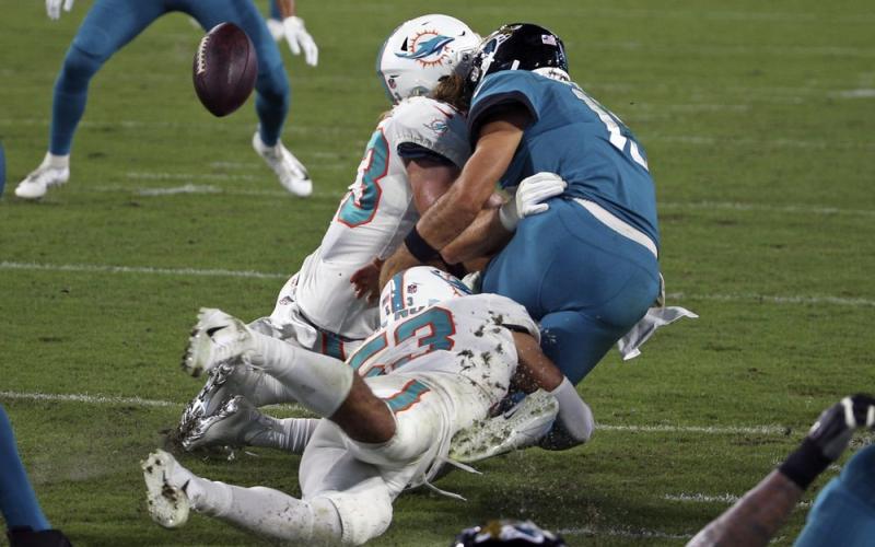 Jacksonville Jaguars quarterback Gardner Minshew, right, fumbles the ball as he is hit by Miami Dolphins outside linebacker Andrew Van Ginkel, left, and middle linebacker Kyle Van Noy during Thursday's game in Jacksonville. (STEPHEN B. MORTON/Associated Press)