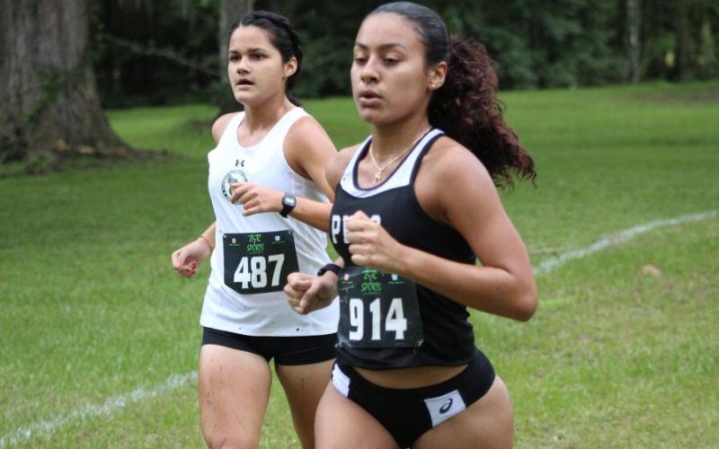 Florida Gateway College runner Merlin Leal (left) runs alongside a Pasco-Hernando State College runner during the Alligator Lake Invitational on Friday. (COURTESY)