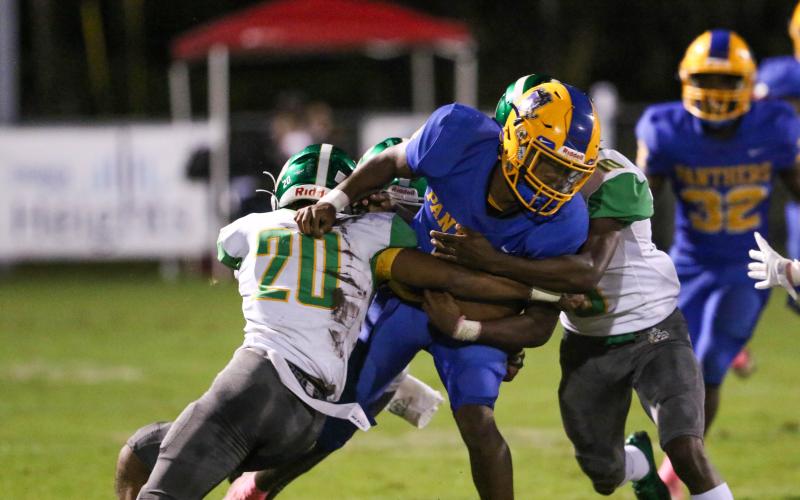 Suwannee’s Travis McKinney (left) and Jay Smith stop Palatka quarterback O’marrion Wilson on a run Friday night. (PALATKA DAILY NEWS)