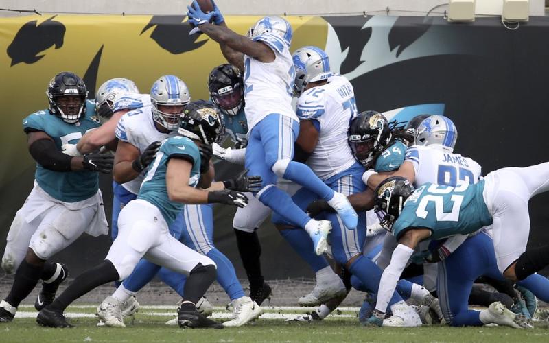 Detroit Lions running back D'Andre Swift (32) leaps over Jacksonville Jaguars linebacker Myles Jack (44) and defensive tackle Taven Bryan (90) for a touchdown on Sunday in Jacksonville. (PHELAN M. EBENHACK/Associated Press)