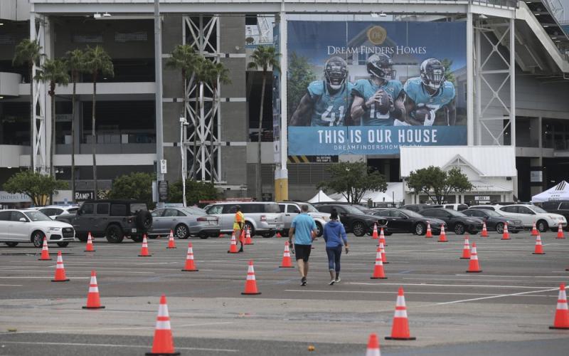 Fans walk through a parking lot with cones to social distance the cars before a game between the Jacksonville Jaguars and the Indianapolis Colts on Sept. 13 in Jacksonville. The Jacksonville Jaguars are the latest NFL team dealing with a positive COVID-19 test. The Jaguars released a statement Saturday, Oct. 17, saying a practice squad player was confirmed as testing positive for the coronavirus a day earlier. (AP FILE PHOTO)