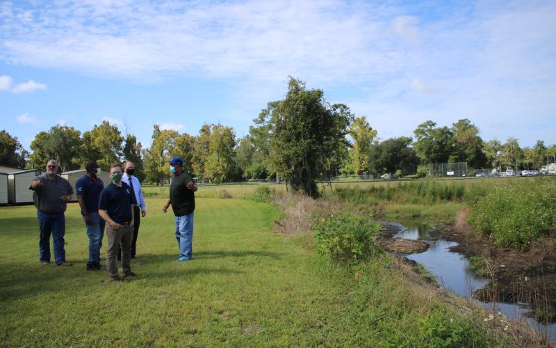 Thomas Henry (clockwise from left), Lake City Public Works Department Director; Leroy Marshall, Suwannee River Water Management District Chief Professional Engineer; Tim Beach, Suwannee River Water Management District Environmental Scientist II; and Joe Helfenberger, city manager, talk to Adee Farmer about drainage issues near a canal near Richardson Community Center. (TONY BRITT/Lake City Reporter)