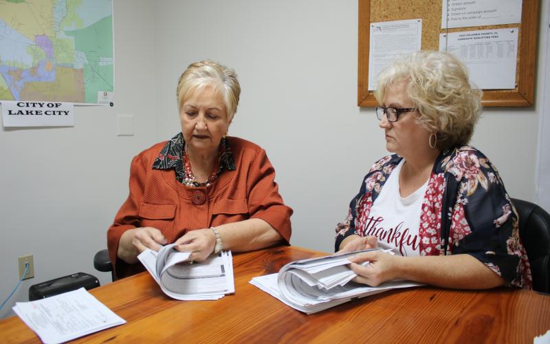Liz P. Horne (left), Columbia County supervisor of elections and Tomi Brown, Columbia County deputy supervisor of elections, look through stacks of voter registrations Monday, the final day to register.  (TONY BRITT/Lake City Reporter)