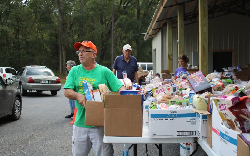 Jim Senzamici grabs a box of food to give to a motorist during a food giveaway at Lake City Church of Thursday afternoon.  (TONY BRITT/Lake City Reporter)