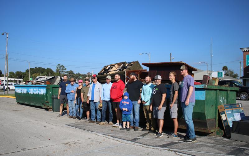 Volunteers stand in front of the overflowing dumpsters from Saturday’s community cleanup event in Lake City. (TONY BRITT/Lake City Reporter)