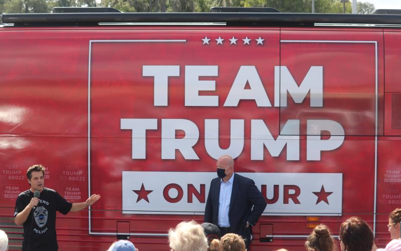 Matt Gaetz, a congressman from Florida’s First District in the panhandle, speaks during Monday’s rally in front of the Trump campaign bus while former acting U.S. Attorney General Matthew Whitaker looks on. More than 150 people attended the campaign stop at the Lake City Plaza. (TONY BRITT/Lake City Reporter)