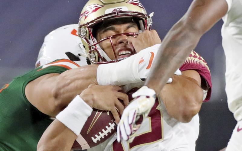 Florida State quarterback Jordan Travis (13) is tackled by a Miami player on Sept. 26 in Miami Gardens. (AL DIAZ/Miami Herald via AP)