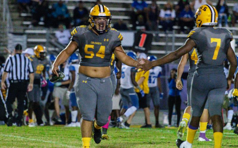 Columbia defensive lineman Jaycob Jones high fives defensive lineman A’deon Farmer as he comes in for a play against Lee last Friday. (RAY CARPENTER PHOTOGRAPHY)