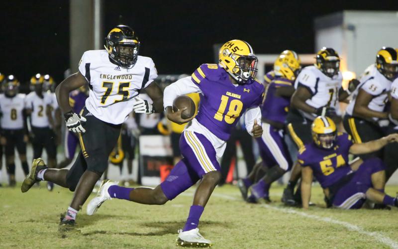 Columbia quarterback Marcus Peterson scrambles past Englewood defensive lineman Andre Vilsaint on Friday night. (BRENT KUYKENDALL/Lake City Reporter)