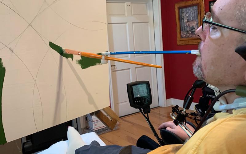 Peter Herrick, a tetraplegic combat veteran from Fort White, paints using a modified paintbursh and a rotating easel. He is the November featured artist at the Gateway Art Gallery. (COURTESY)