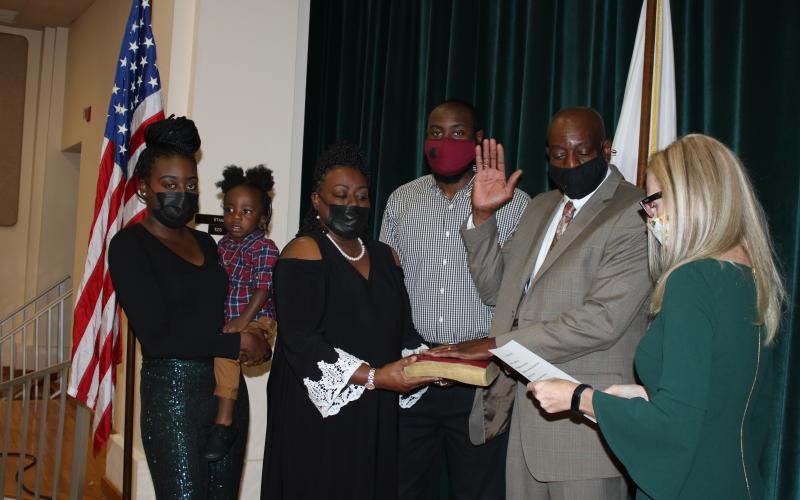 Da’Breah J. Hill (from left), Onyx  A. Jones, Deborah J. Hill, Ja’Keem A. Hill and Jake Hill listen to Audrey Sikes, city clerk, as she leads Jake Hill in his oath of office. Hill was sworn-in to another term as a city council member Monday evening. (TONY BRITT/Lake City Reporter)