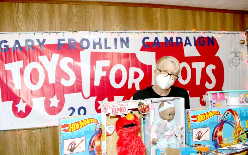 Inga Dwyer, Toys for Tots coordinator for Columbia and Suwannee counties, stands behind a row of toys in her office on Wednesday. (TONY BRITT/Lake City Reporter)