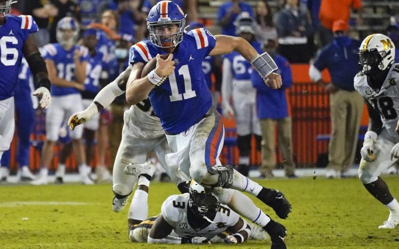 Florida quarterback Kyle Trask (11) runs past Missouri's Martez Manuel (3) and linebacker Nick Bolton, back left, this past Saturday in Gainesville. (JOHN RAOUX/Associated Press)