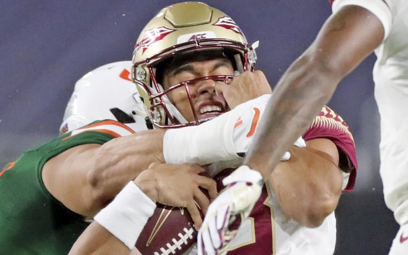 Florida State quarterback Jordan Travis (13) is tackled by a Miami player on Sept. 26 in Miami Gardens. (AL DIAZ/Miami Herald via AP)