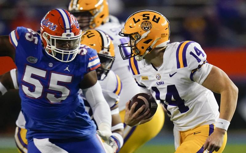 LSU quarterback Max Johnson (14) scrambles past Florida defensive lineman Kyree Campbell (55) on Saturday in Gainesville. (JOHN RAOUX/Associated Press)