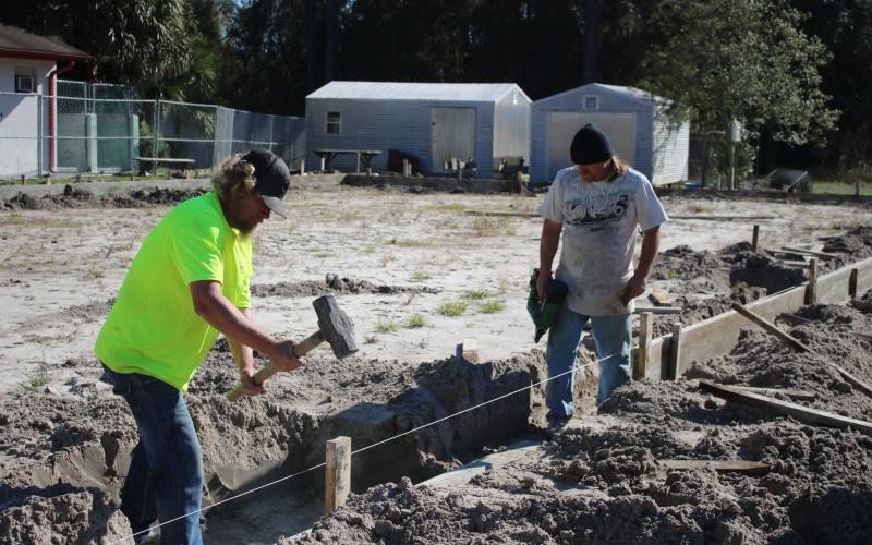 William Glover (left) and Kerry DeYoung put stakes in the ground Wednesday afternoon while doing preparation work for the James Montgomery Animal Wellness Center at the Lake City-Columbia County Humane Society. (TONY BRITT/Lake City Reporter)