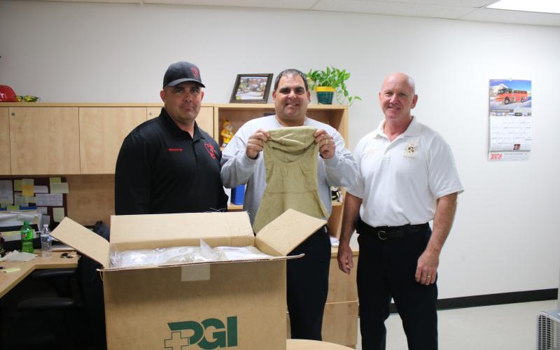 Billy Brideson (from left), owner of 3rd Alarm Public Safety Training, stands with Tad Cervantes, CCFR assistant chief and Jeff Crawford, CCFR  Chief, as they a show a new hood county firefighters will receive. The Nomex particulate hoods increase firefighter safety against carcinogens. The county fire department recently purchased 54 of the hoods with funds raised through a 3rd Alarm training session. (TONY BRITT/Lake City Reporter)